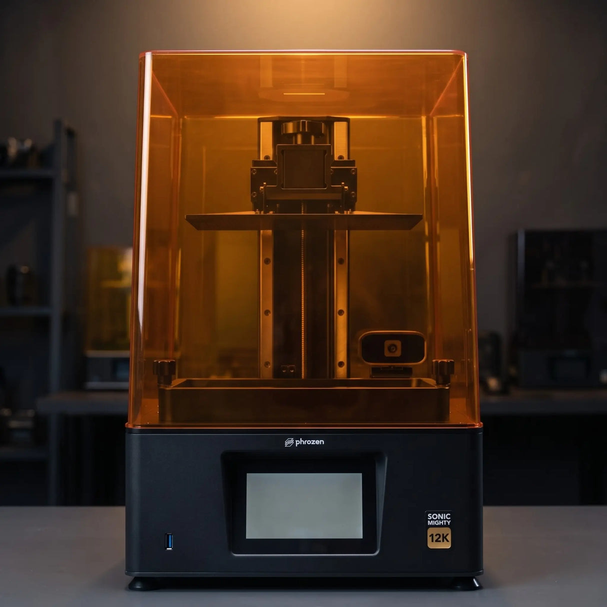 Phrozen Sonic Mighty 12K resin 3D printer front view on dark studio desk with warm pendant lighting