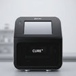 Phrozen Cure+ dental resin curing unit, front view, showing the touchscreen display and curing chamber.