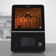 Phrozen Sonic LS+ dental resin 3D printer, front view, with an amber lit chamber showing a printed dental arch model attached to the build plate.