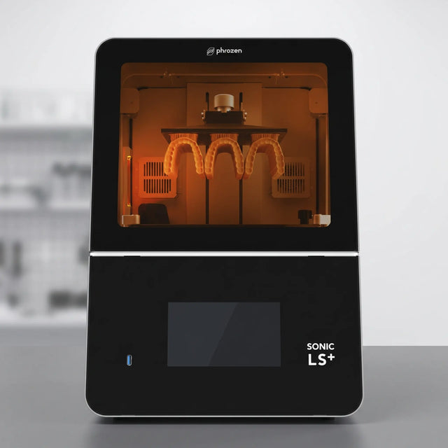 Phrozen Sonic LS+ dental resin 3D printer, front view, with an amber lit chamber showing a printed dental arch model attached to the build plate.