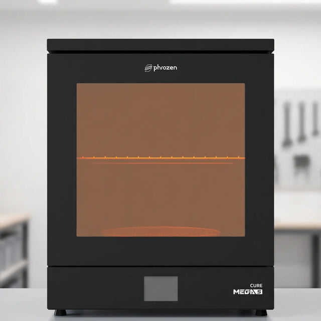 Phrozen Cure Mega S resin curing station with glowing interior on light grey workshop shelf