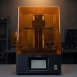 Phrozen Sonic Mighty 12K resin 3D printer front view on dark studio desk with warm pendant lighting