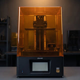 Phrozen Sonic Mighty 12K resin 3D printer front view on dark studio desk with warm pendant lighting