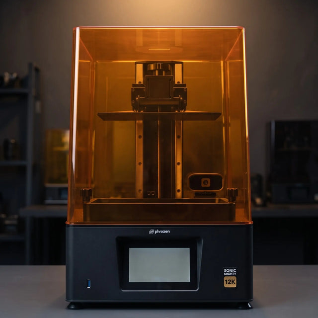 Phrozen Sonic Mighty 12K resin 3D printer front view on dark studio desk with warm pendant lighting