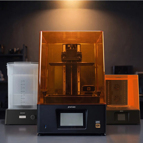 Phrozen Sonic Mighty 12K resin 3D printer with wash station and cure station on dark studio desk with warm pendant lighting